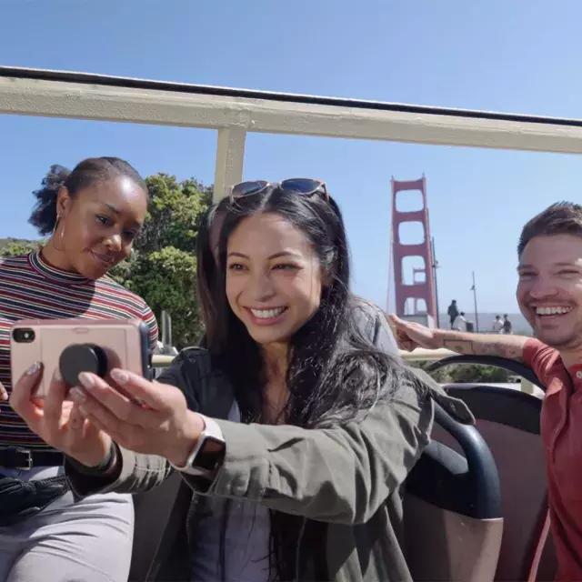 Un grupo de visitantes se toma una selfie en un recorrido en autobús cerca del puente Golden Gate. 贝博体彩app，加州.