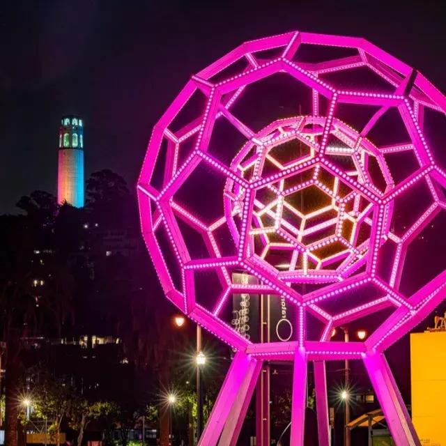 Buckyball leuchtet vor dem Exploratorium, im Hintergrund der Coit Tower